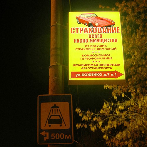 Ночной вид рекламного указателя на опоре уличного освещения
